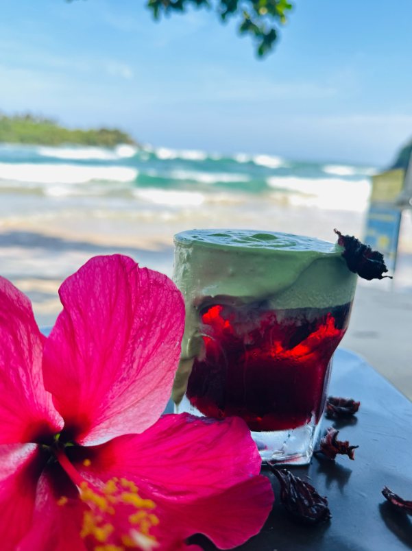 A hibiscus iced drink with matcha foam on the beach