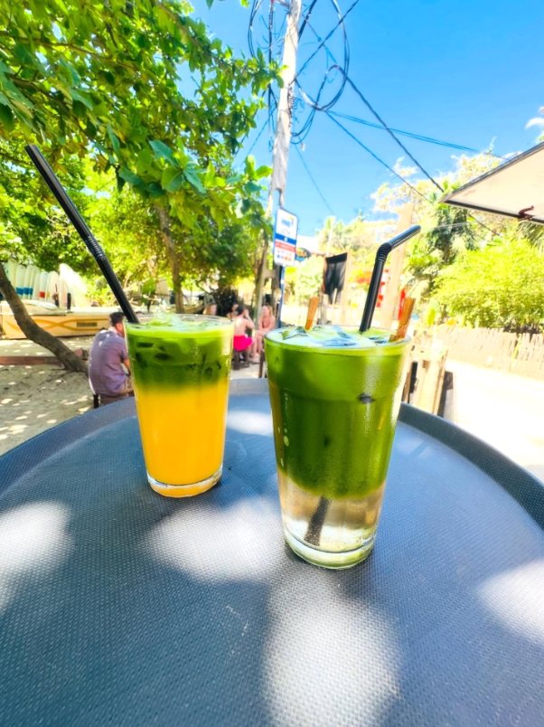 Two layered iced matcha drinks on a table outside